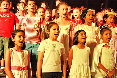 Primary students wholeheartedly sing “We are Children of the World”.